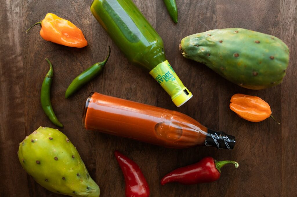 Vibrant display of hot sauces and peppers on a wooden surface, perfect for culinary themes.